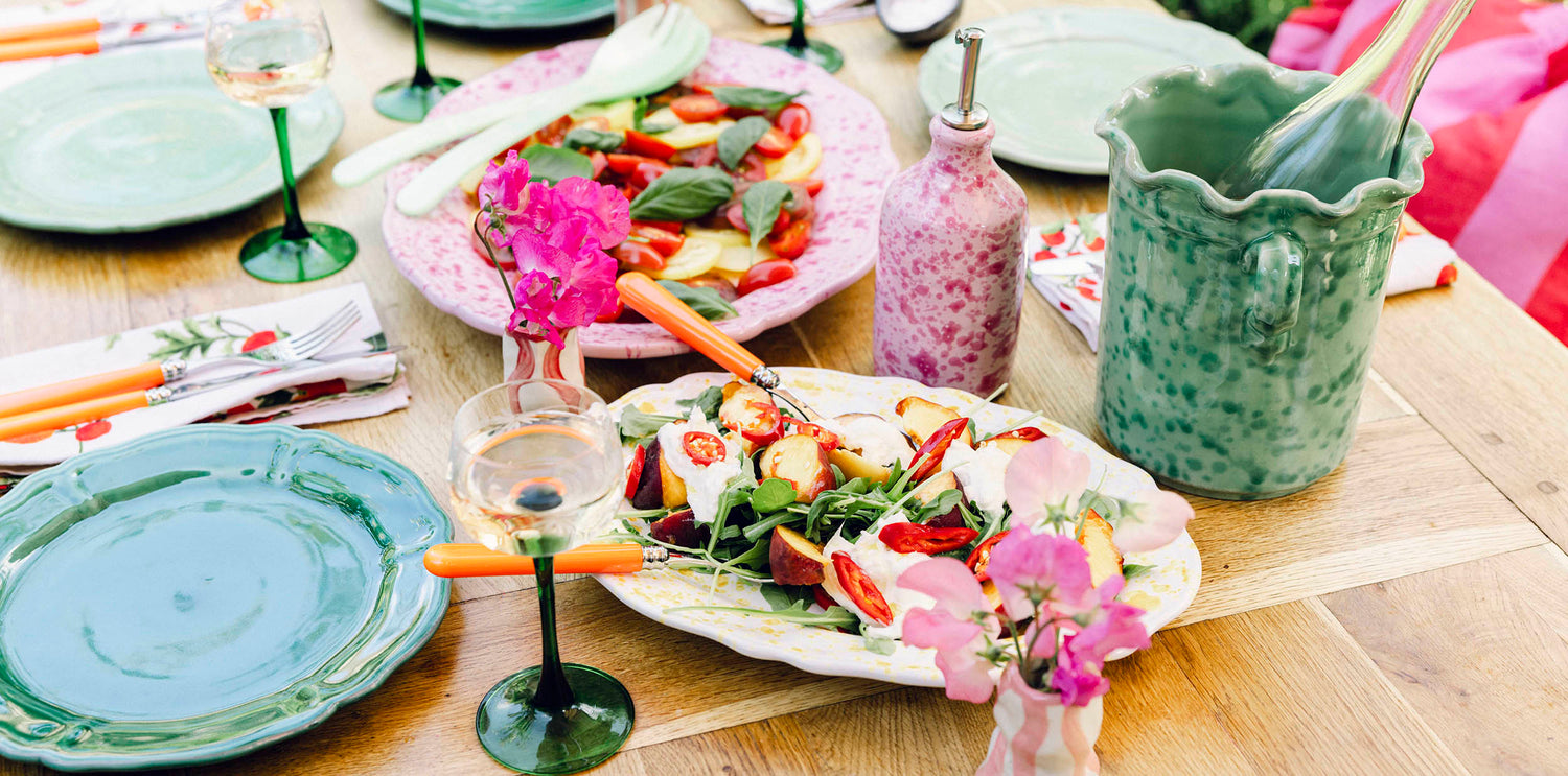 Summer salad with pink and green tableware on garden table