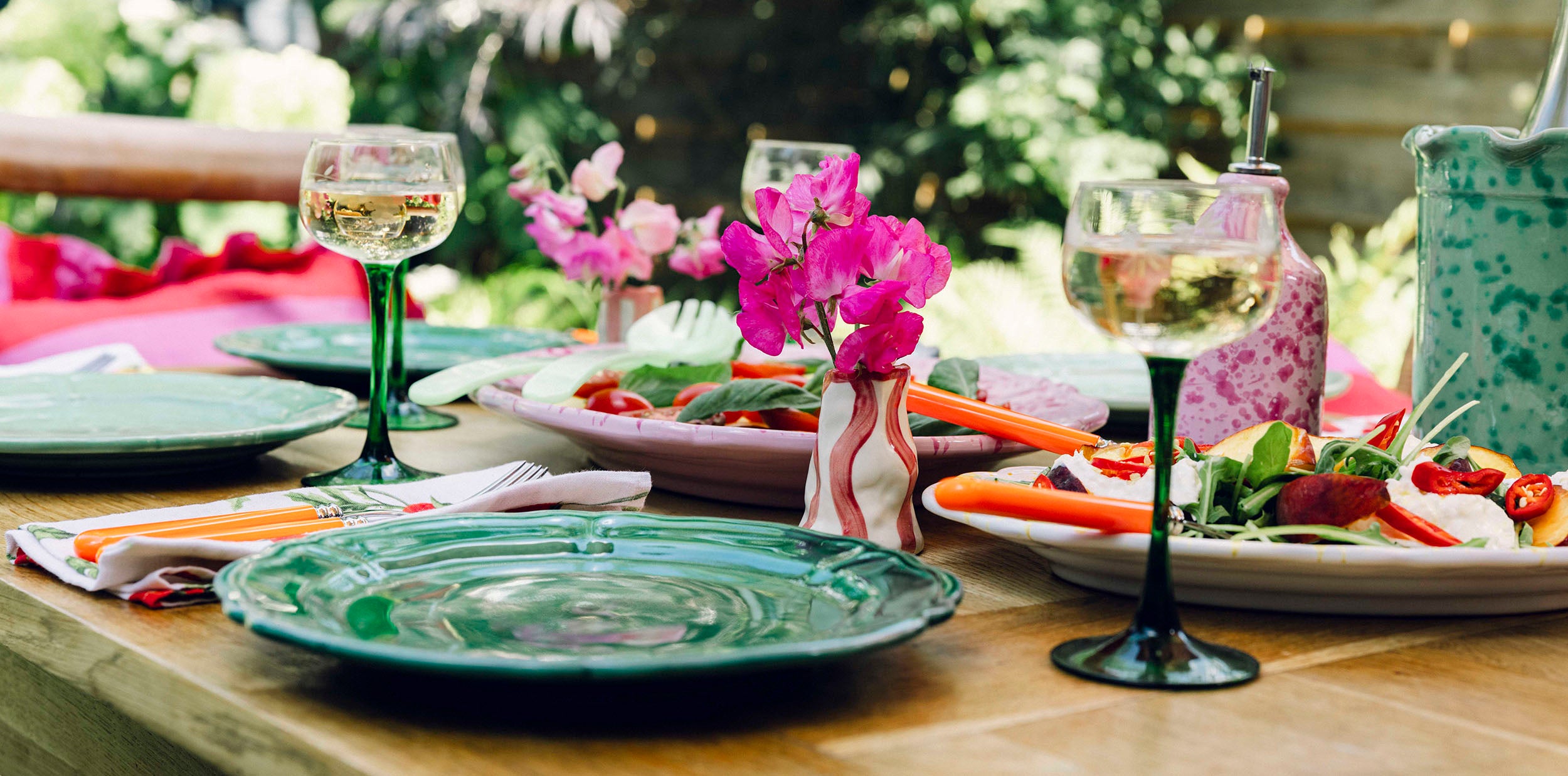 Summer salad on garden table with vintage wine glasses and green plates