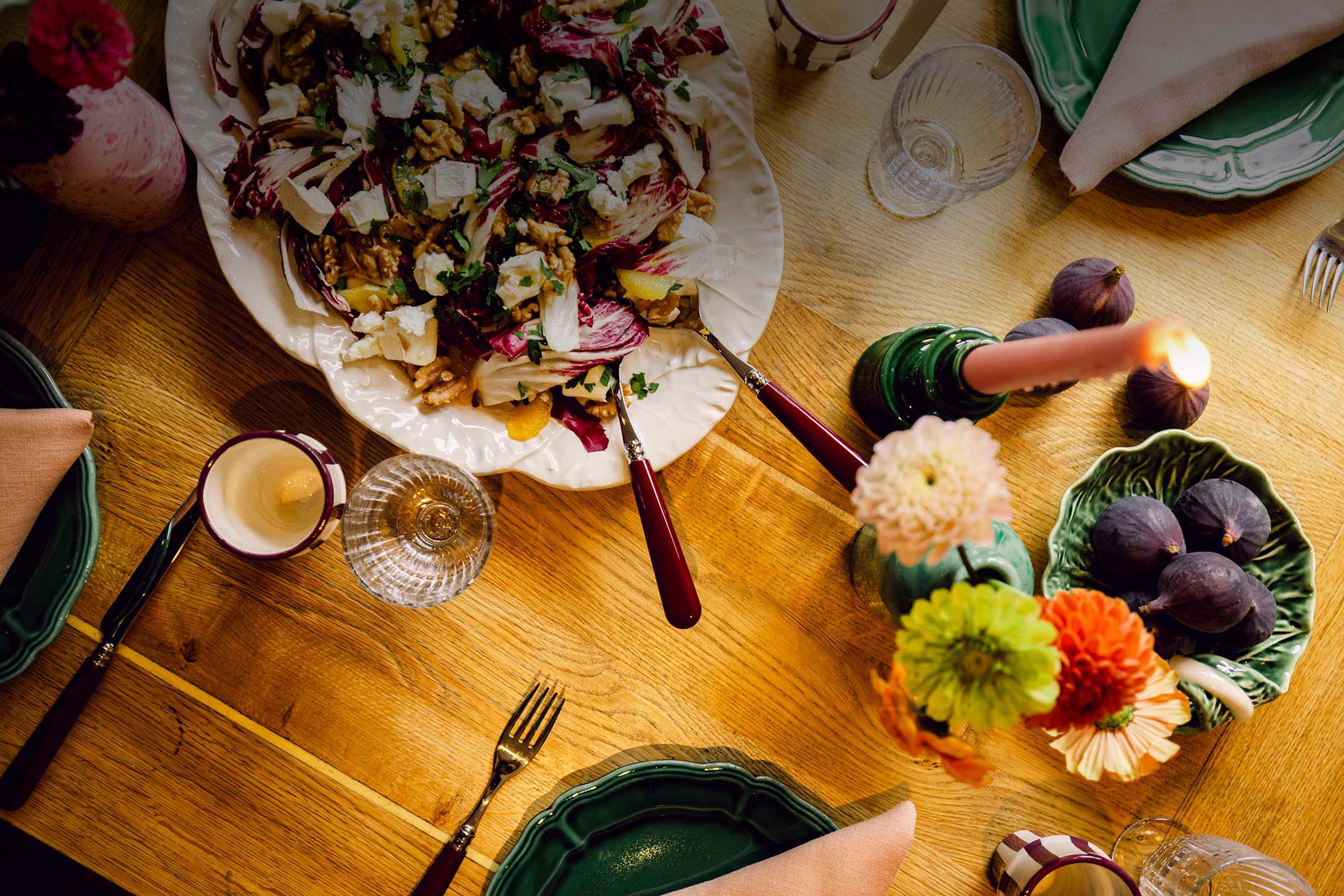 Table top of autumnal salad, bowl of figs and candles