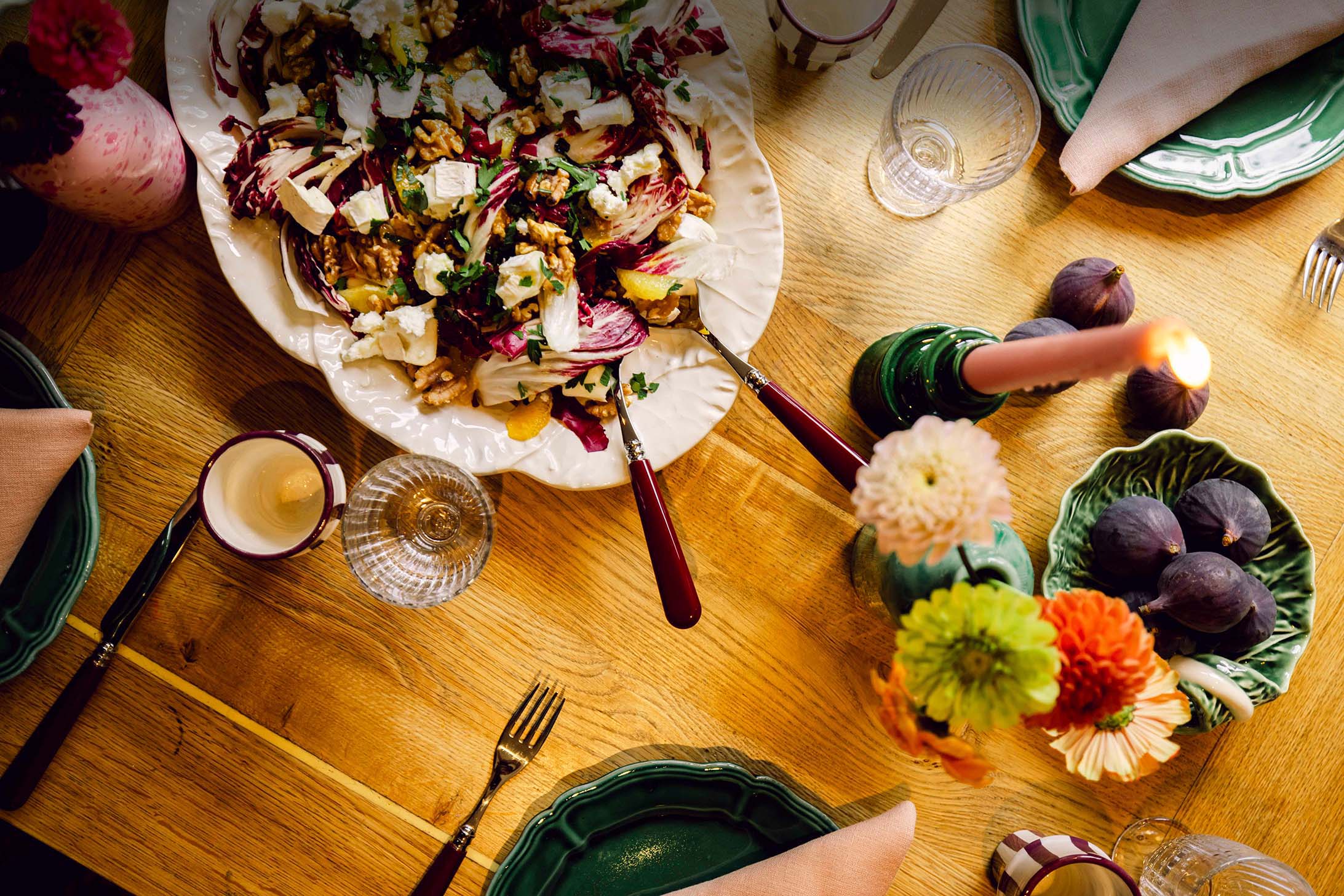 Table top of autumnal salad, bowl of figs and candles